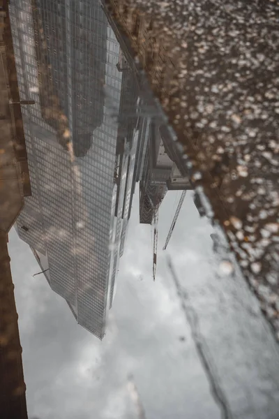 Vertikální Záběr Kaluže Odrážející Vysoké Moderní Budovy Deštivého Dne Londýně — Stock fotografie