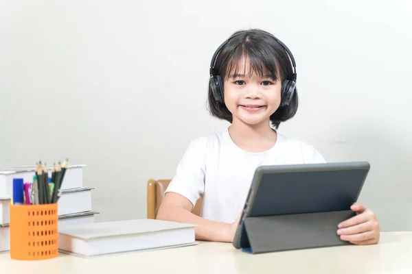 Ein Asiatisches Mädchen Trägt Kopfhörer Und Macht Hausaufgaben Auf Einem — Stockfoto