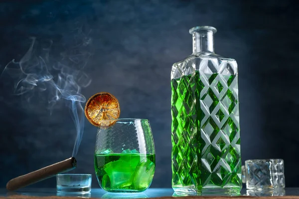 Uma Vista Decantador Copo Com Uma Bebida Verde Charuto Perto — Fotografia de Stock