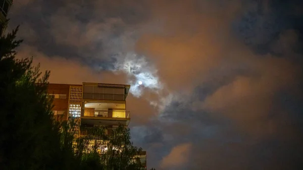 在乌云密布的夜空中 房子的灯光闪烁着 — 图库照片