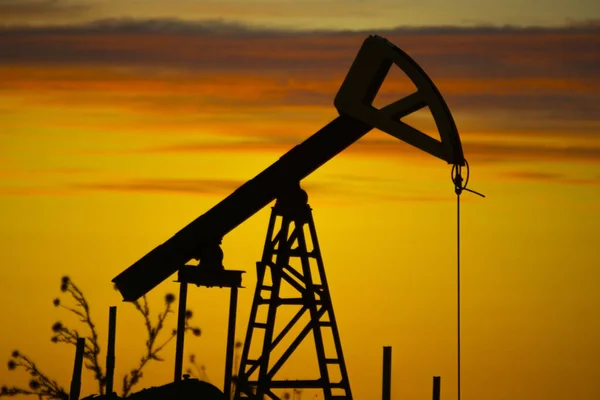 日落天空背景上的石油抽油机轮廓 — 图库照片