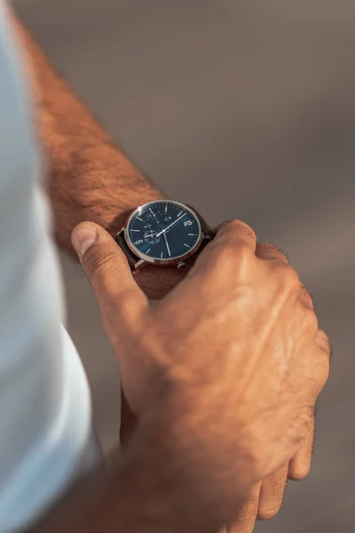 A vertical shot of a male checking the time on his watch