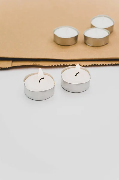 一排排的白色香蜡茶灯放在白色台面上 带有复制空间和折叠纸袋 — 图库照片