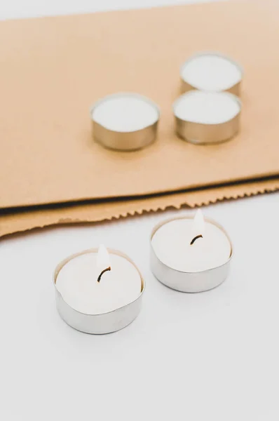 一排排的白色香蜡茶灯放在白色台面上 带有复制空间和折叠纸袋 — 图库照片