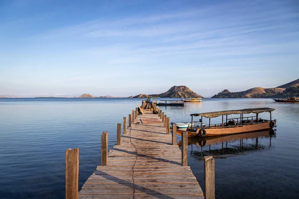 Scuba Diving boats moored to a small wooden jetty in Komodo Nature Reserve at sunrise.