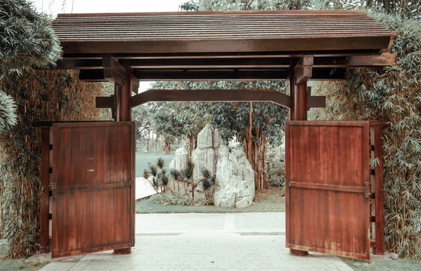 高密度の植生と石片を持つ美しい公園につながる和風の木製の門 — ストック写真