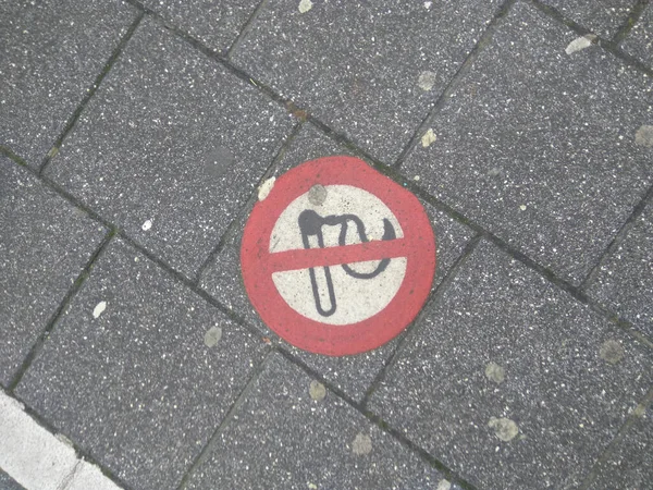 The red round No Smoking sign on the ground of the sidewalk