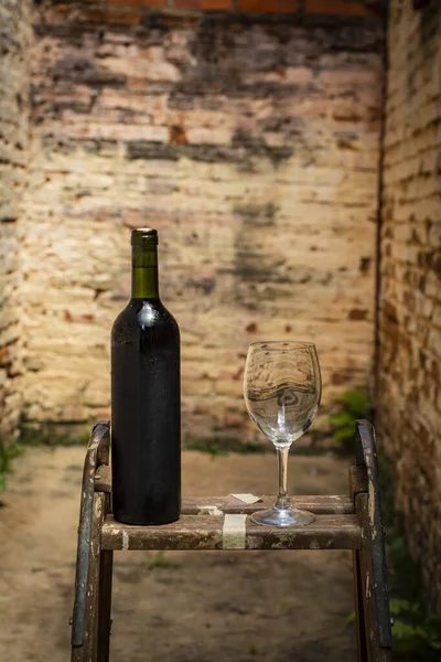 レトロな窓に赤ワインと空のワイングラスのボトルの垂直ショット — ストック写真