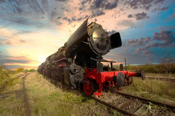 在美丽的落日和云彩映衬下铁路上的蒸汽机车 — 图库照片