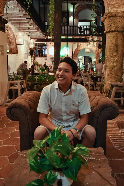 Svislý Záběr Mladého Kolumbijského Muže Sedícího Židli Restauraci Usmívajícího — Stock fotografie