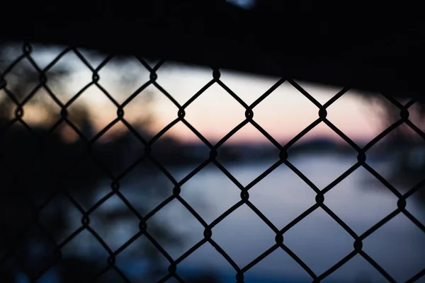 Close Uma Cerca Arame Com Lago Pôr Sol Fundo Borrado — Fotografia de Stock