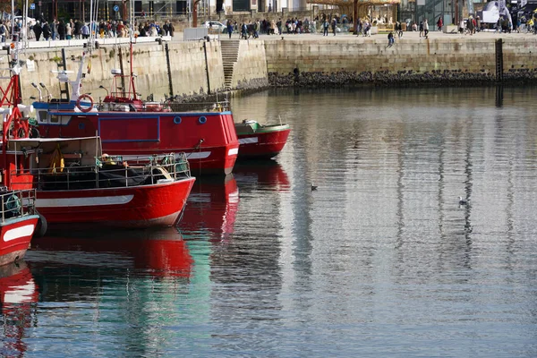 在阳光明媚的日子里 红色的船停泊在港口 人们在岸边等着 — 图库照片