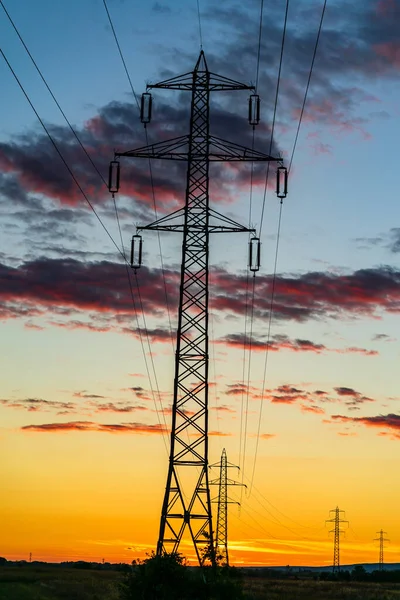 夕方の美しい夕日の間に太陽の下で送電塔の垂直ショット — ストック写真