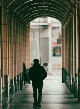 CALGARY, CANADA - Oct 24, 2021: A young man walking through an arching corridor in Calgary downtown in Alberta clipart