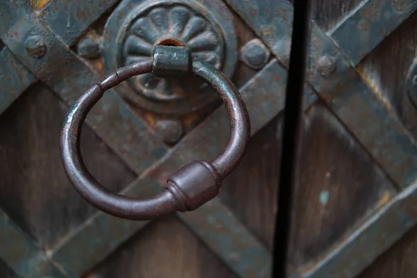 A close up shot of an old and rusty gate holder on an aged gate with wood and metal