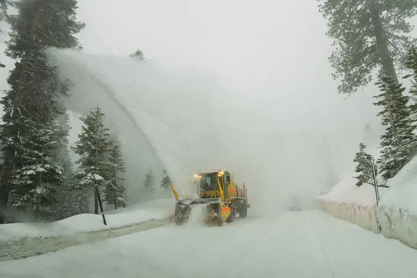 A snow cleaning machine working on white snow-covered street on a gloomy day
