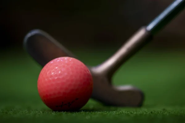 一个红色高尔夫球的特写镜头 旁边有一个高尔夫球杆 背景模糊 — 图库照片