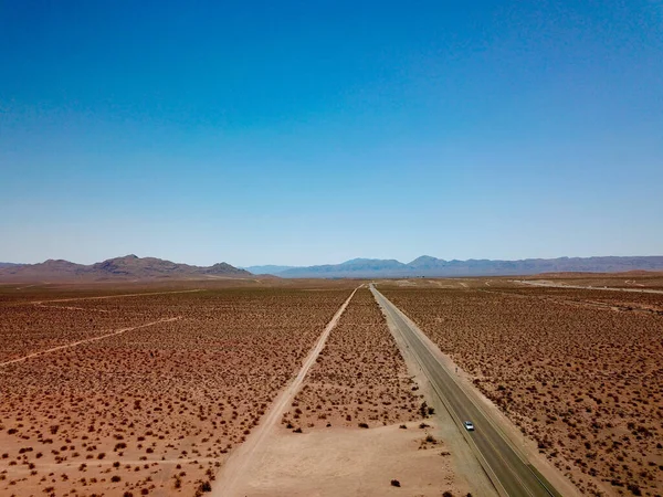 背後に丘のある野生の砂漠のようなフィールド間の道路の美しい景色 — ストック写真