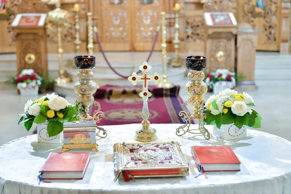 A round table with missals, candle holders and decorative flowers in the church arranged for wedding