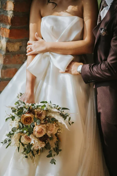 新郎和新娘的一张垂直的照片 新娘手里拿着一束美丽的玫瑰 — 图库照片