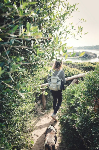 日光の下で木の間の歩道を歩くバックパックを持つ白人の少女の垂直ショット — ストック写真