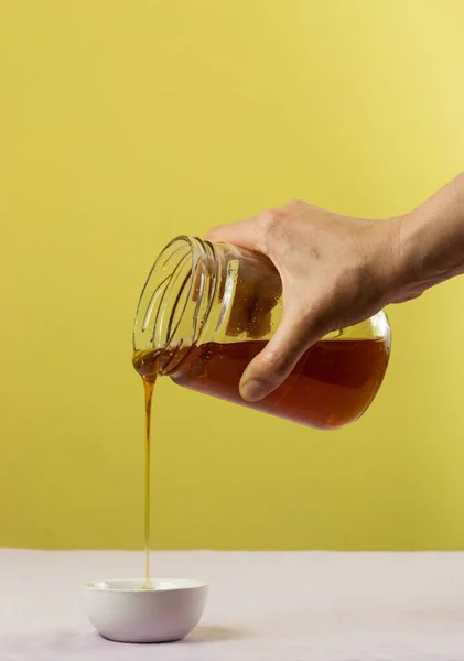 Eine Hand Gießt Honig Aus Einem Glas Über Eine Weiße — Stockfoto