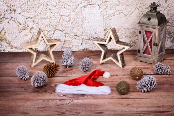 Weihnachtsmütze Holzsterne Tannenzapfen Und Eine Holzlaterne Auf Holzboden Vor Steinmauer — Stockfoto