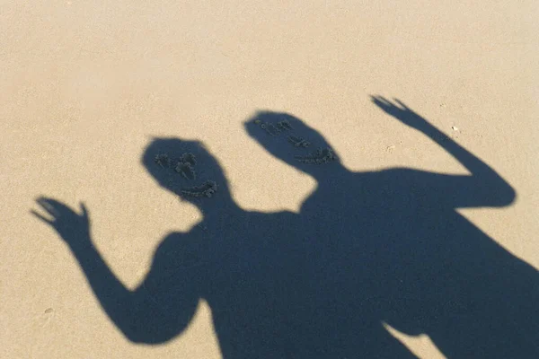 Ombre Due Uomini Sulla Sabbia Della Spiaggia Con Volti Disegnati — Foto Stock
