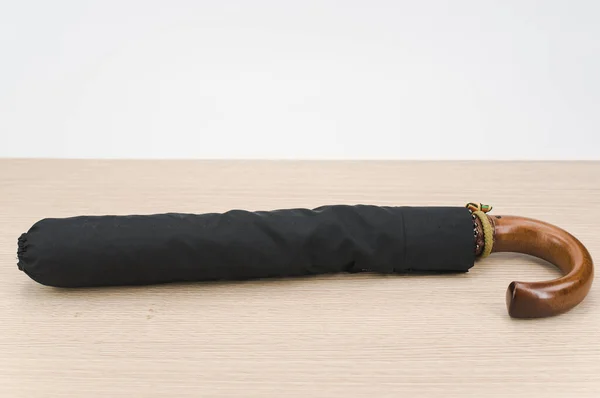 Black Foldable Umbrella Solid Wood Handle Wooden Surface Copy Space — Zdjęcie stockowe