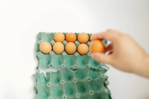 一只手从白色背景的纸盒中取出鸡蛋 — 图库照片