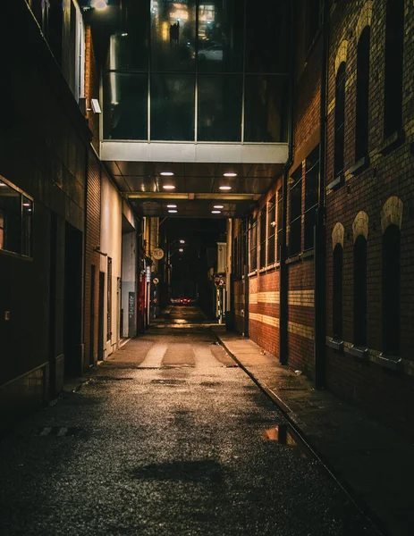 Vertical Shot Dark Alley Night Footbridge Old Style Brick Buildings — Zdjęcie stockowe