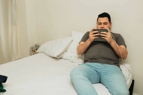 Ένας Ισπανόφωνος Άντρας Κάθεται Στο Κρεβάτι Του Και Χρησιμοποιεί Smartphone — Φωτογραφία Αρχείου