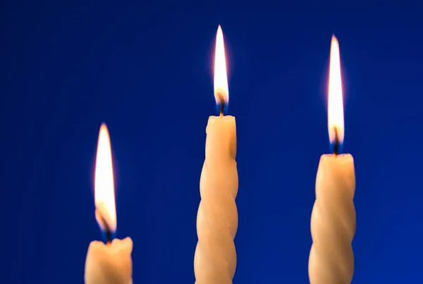 Drie Aangestoken Kaarsen Geïsoleerd Een Blauwe Achtergrond — Stockfoto