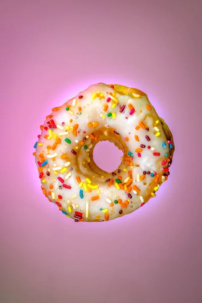 Eine Vertikale Aufnahme Eines Donuts Mit Weißem Zuckerguss Und Regenbogenbestreuungen — Stockfoto