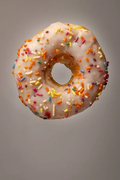 Vertical Shot Donut White Frosting Rainbow Sprinkles White Background — Stockfoto