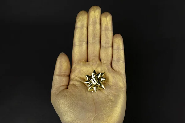 Złota Ręka Miniaturowym Łukiem Prezentów Odizolowana Czarnym Tle — Zdjęcie stockowe