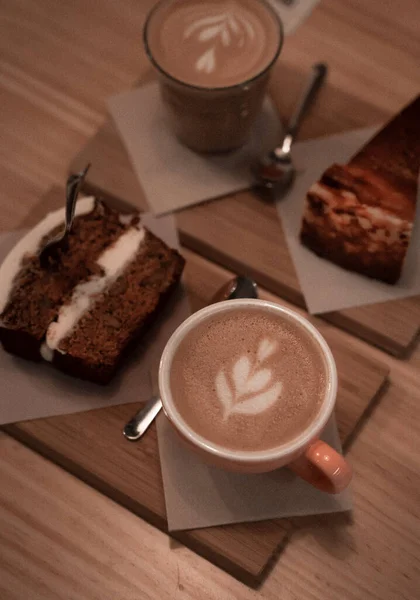 Tiro Vertical Porções Cappuccino Fatias Bolo Uma Mesa Madeira — Fotografia de Stock