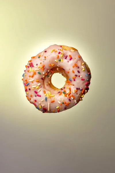 Eine Vertikale Aufnahme Eines Donuts Mit Weißem Zuckerguss Und Regenbogenbestreuungen — Stockfoto