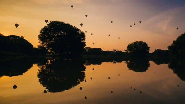 Silhouetten Van Hete Lucht Ballonnen Vliegen Een Meer Tijdens Zonsondergang — Stockfoto