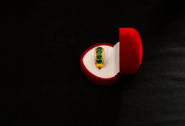 stock image KUALA LUMPUR, MALAYSIA - Oct 07, 2021: A beautiful, luxury golden ring with green crystals in the red box isolated on the black background