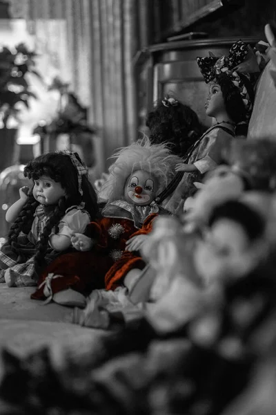一个可怕的小丑娃娃和其他几个娃娃坐在沙发上 其中包括一个被吓到的左撇子 — 图库照片