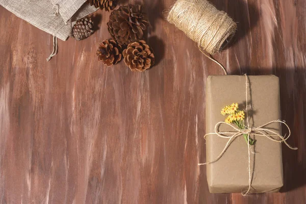 一张用松果和细绳包裹在木制桌子上的圣诞礼物的头像 — 图库照片