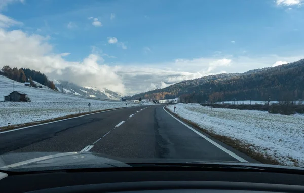 雪に覆われたアルプスの山々と電気自動車のフロントガラスの後ろから移動中のショット 寒い曇りの秋の日 — ストック写真