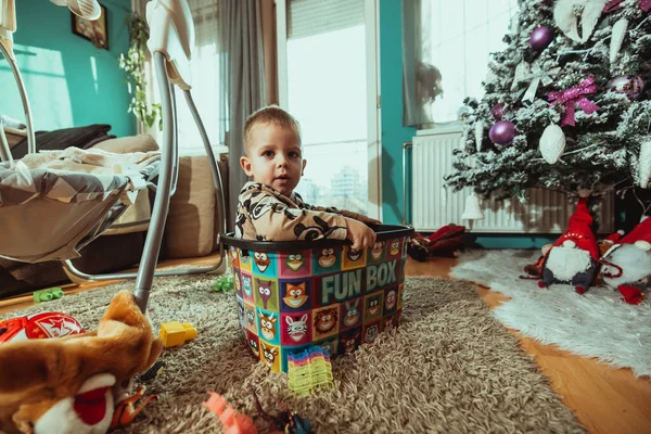 Adorabile Bambino Seduto Una Scatola Giocattoli Una Stanza Soleggiata Con — Foto Stock