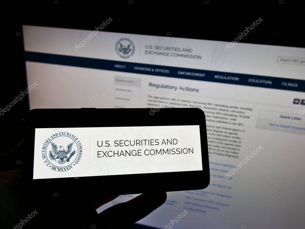 STUTTGART, GERMANY - Dec 05, 2021: Person holding cellphone with logo of American agency Securities and Exchange Commission (SEC) on screen in front of webpage. Focus on phone display.