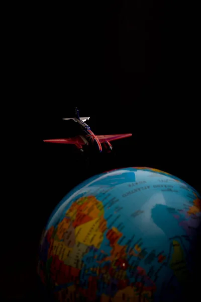 黑暗背景下的玩具飞机和地球仪的垂直照片 — 图库照片