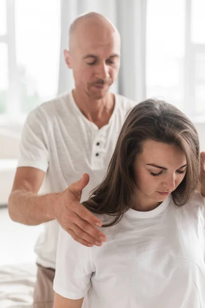 Professional Young Man Massaging Woman Neck White Cozy Room Manual — Stockfoto