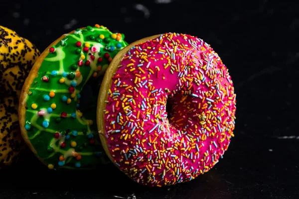 Closeup Shot Donuts Glazed Sprinkles Black Background — Stockfoto