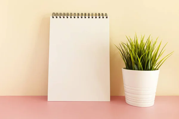 Ένα Λευκό Σπειροειδές Σημειωματάριο Ένα Φυτό Παστέλ Φόντο — Φωτογραφία Αρχείου