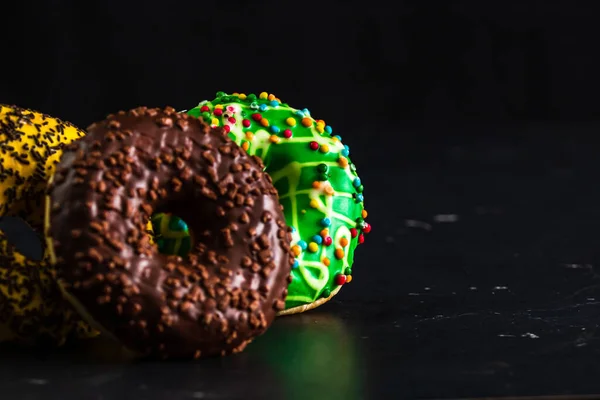 Eine Nahaufnahme Von Donuts Mit Glasierten Streusel Auf Schwarzem Hintergrund — Stockfoto